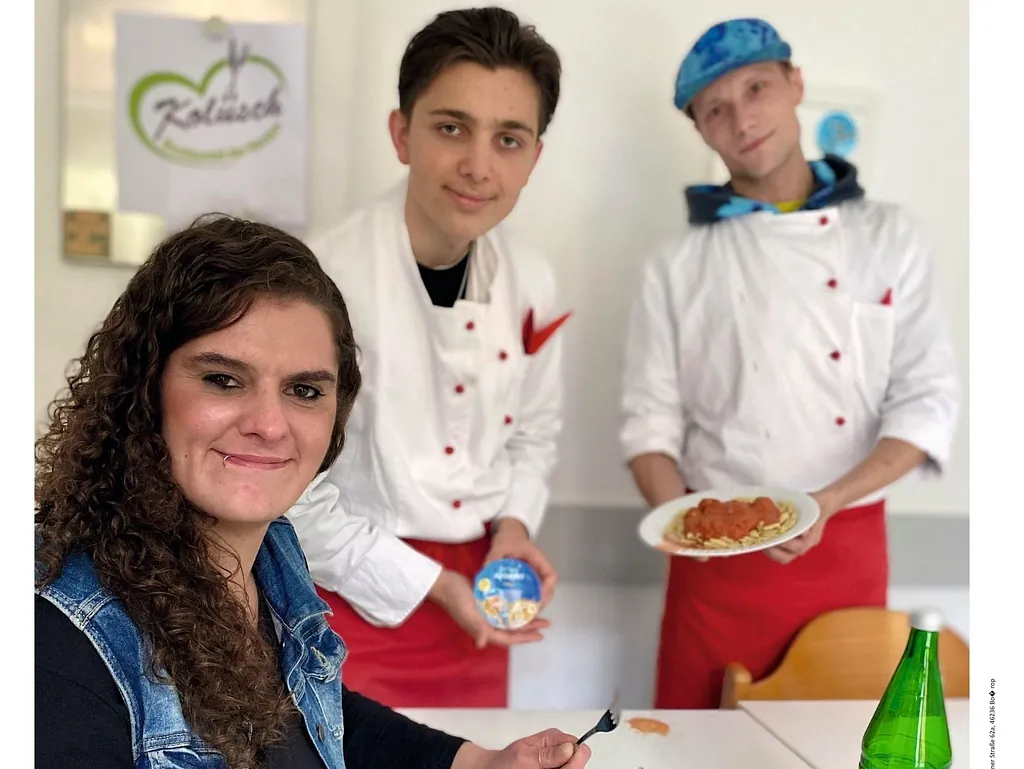 Eine Frau hält eine Gabel, ein Mann hält einen Joghurt und ein anderer Mann hält einen Teller mit Essen in der Hand
